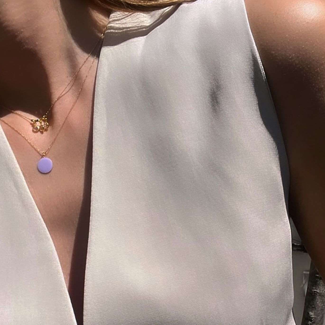 Buste de femme portant un collier avec une chaine et un médaillon de couleur lila