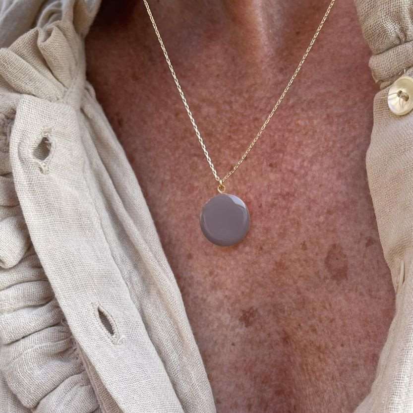 Buste de femme portant un collier avec une chaine et médaillon de couleur marron