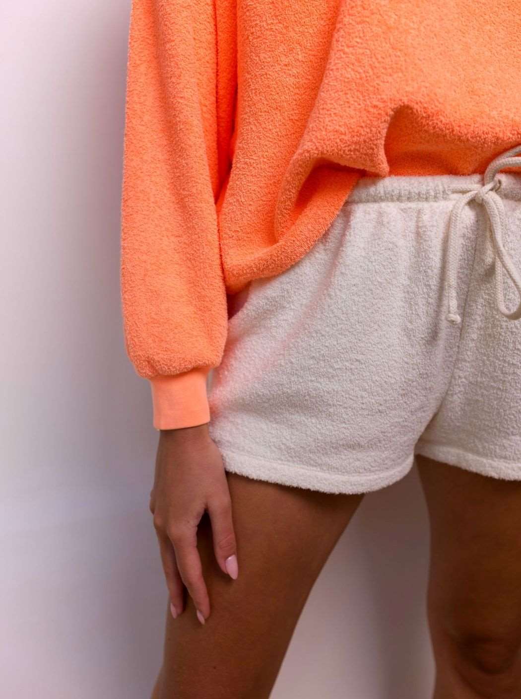 Femme portant un short clair et un pull orange fluo en matière éponge