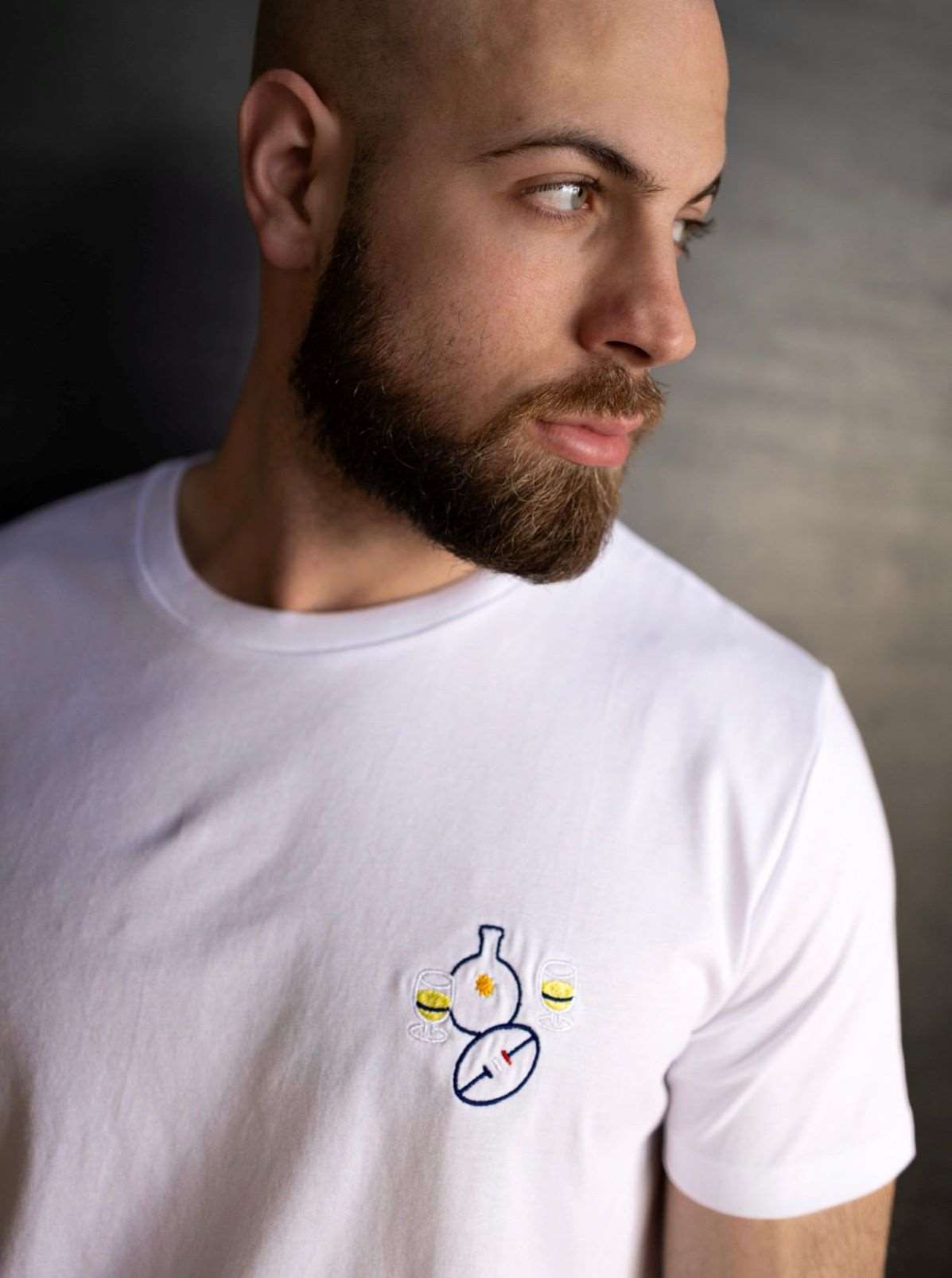 Homme portant un t-shirt blanc minimaliste avec une petite broderie de verres de pastis